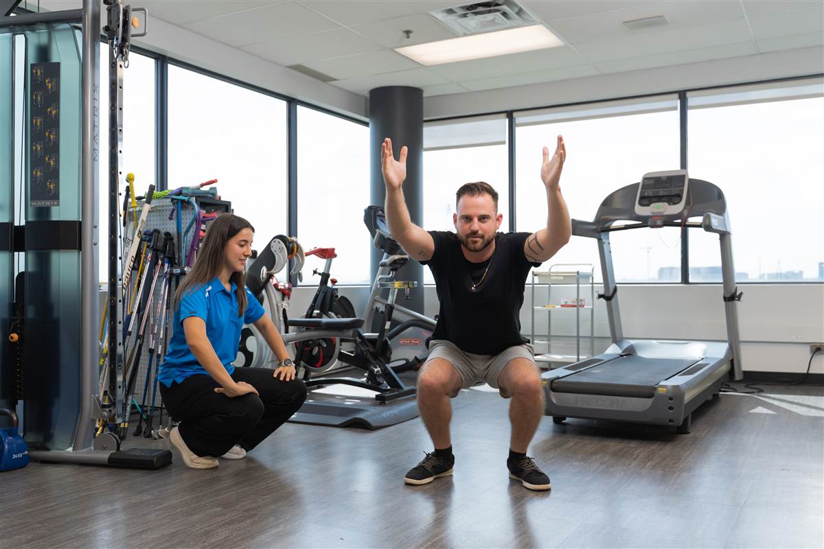 Une physiothérapeute guide un patient dans un squat