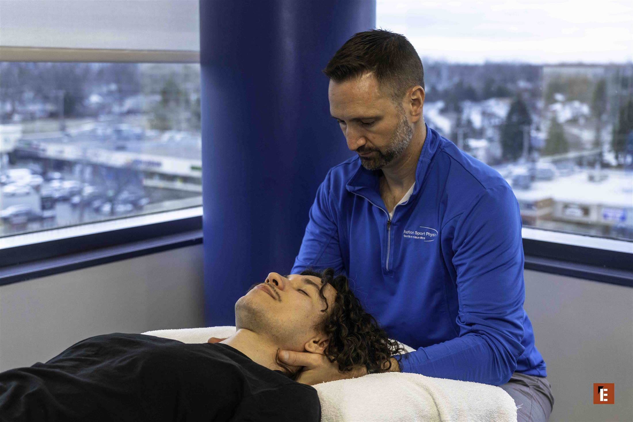 Une physiothérapeute traite le cou d’une patiente près de la fenêtre
